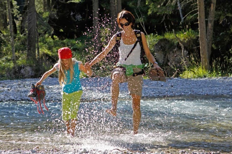 Mama mit Kind wandern durch Bach © Shutterstock